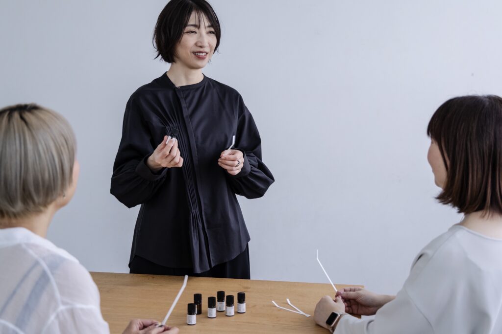 アロマのレッスンの様子。精油とムエットを持った講師が生徒さんに話している様子。