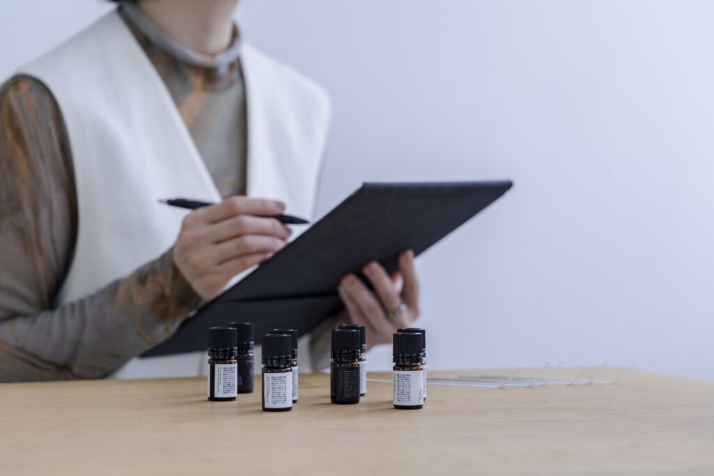 机の上には精油、手元のボードに何かを書いている女性