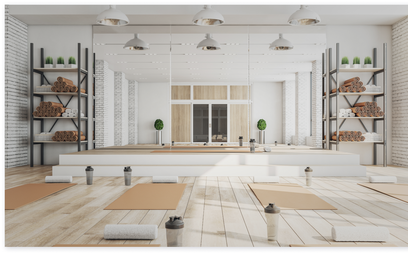 ヨガスタジオ(壁一面の大きな鏡、床にはヨガマット、タオル、ドリンクが置かれている)